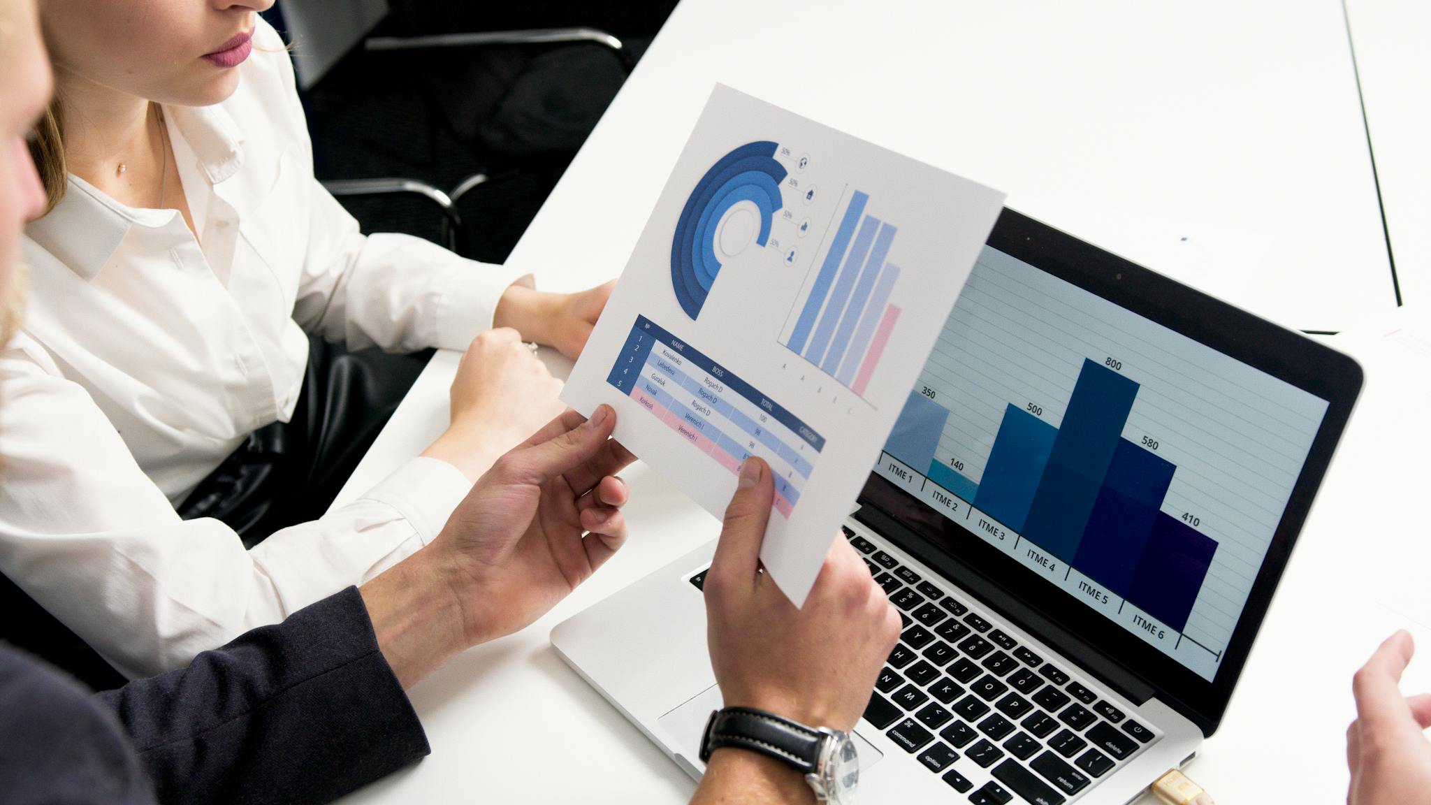 Home Business professionals discussing data charts and graphs in a modern office setting.