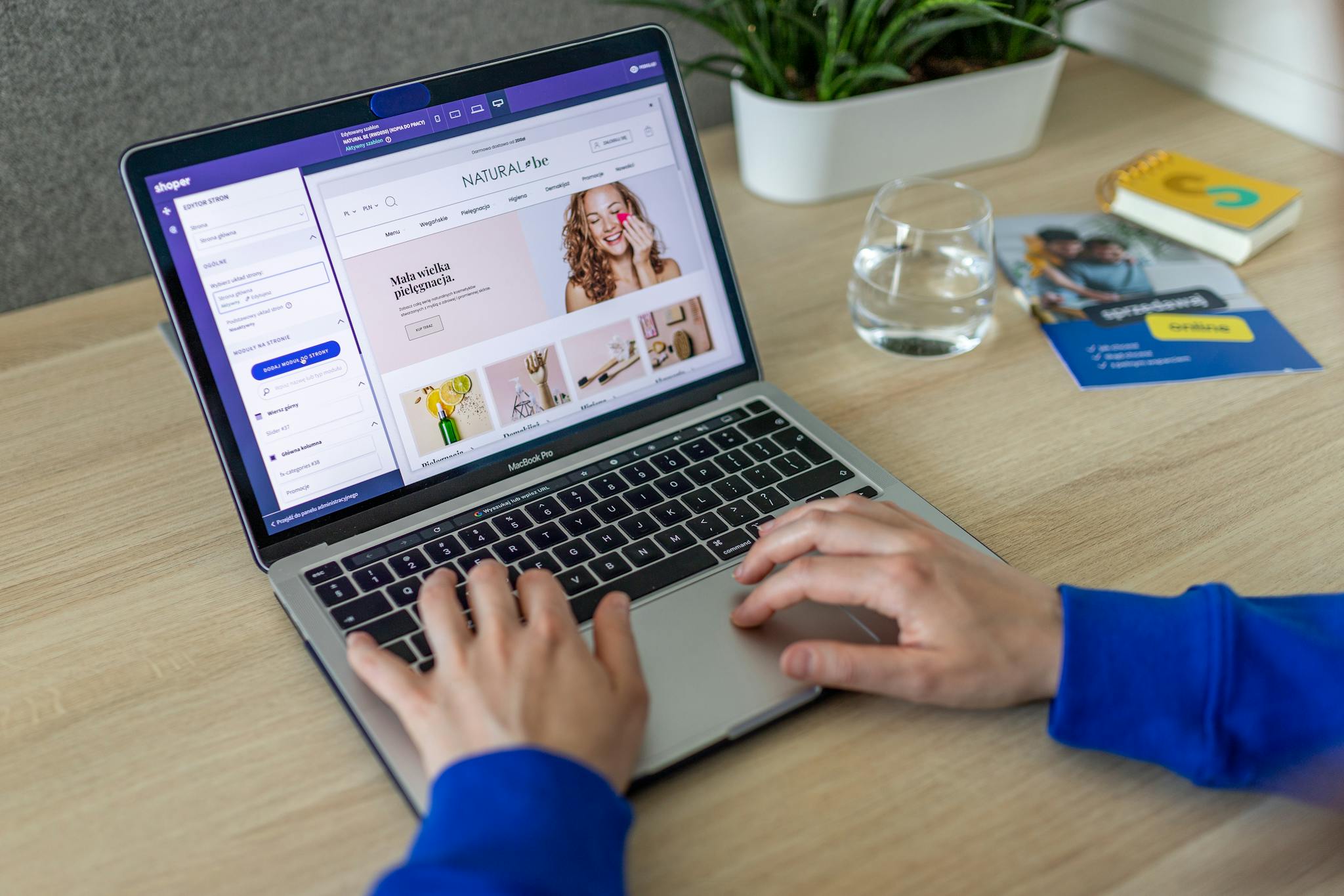 About Hands typing on a laptop showing an e-commerce website in a modern office setting.