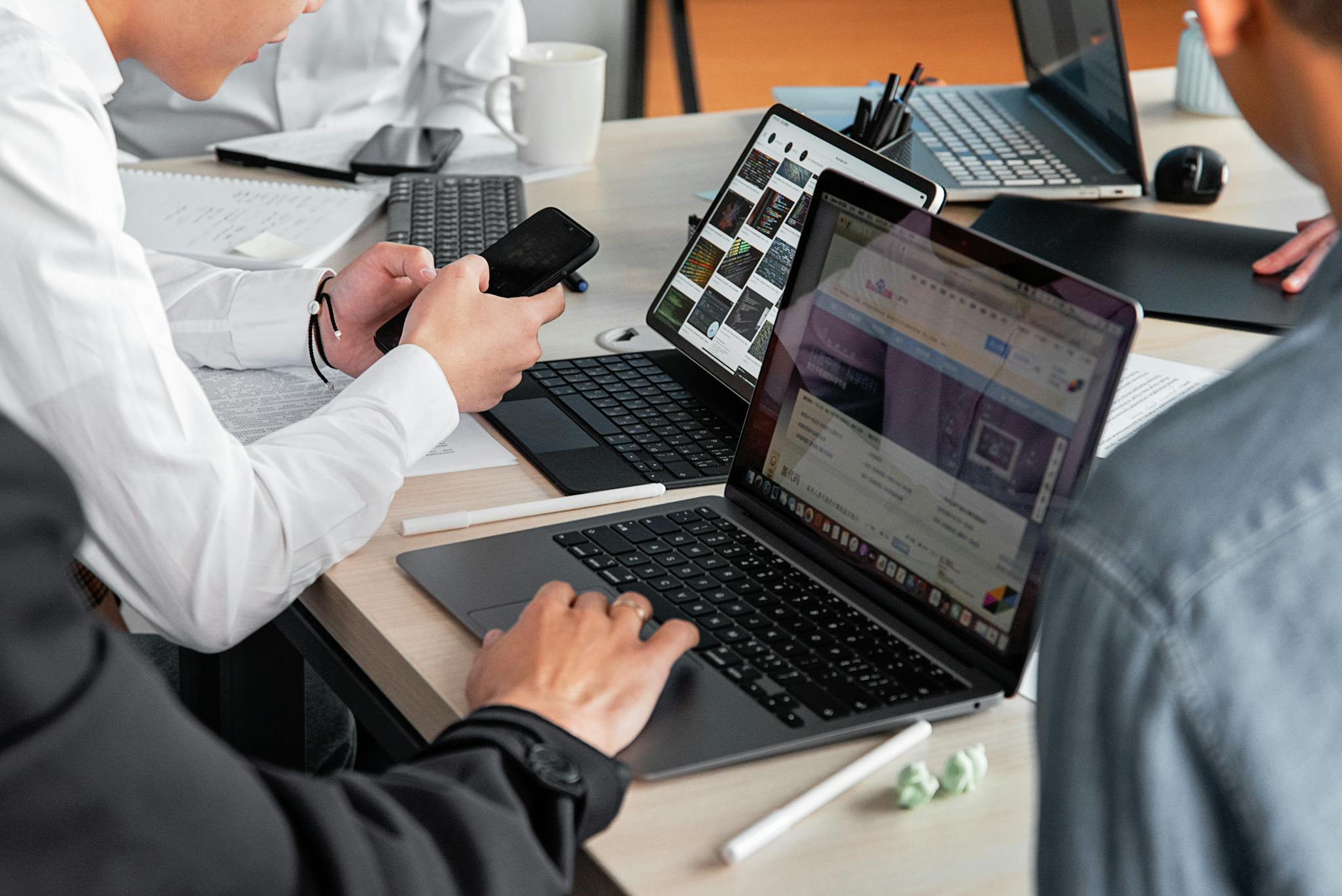 Home Professionals in a modern office discussing work with laptops and smartphones.